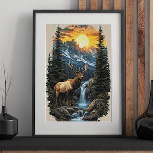 May include: Framed art print featuring a majestic elk standing near a waterfall in a mountain landscape. The artwork showcases a vibrant sunset with a large sun, snow-capped mountains, and tall evergreen trees. The print is encased in a black frame.