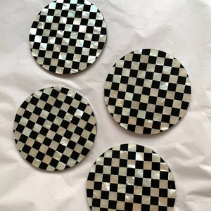 May include: Set of four round black and white checkered coasters made of mother of pearl.