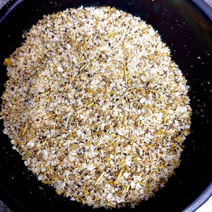 May include: A close-up of a black bowl filled with a mixture of dried herbs, salt, and pepper.