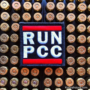 May include: A black patch with a red and white border. The patch has the text "RUN PCC" in white letters on a black background.