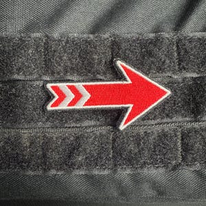 Peut inclure: Une flèche rouge avec des chevrons blancs sur un fond noir. La flèche pointe vers la droite.