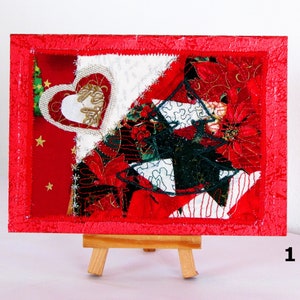 Könnte beinhalten: Ein festliches Kunstwerk zum Thema Weihnachten mit rotem Rahmen. Das Kunstwerk zeigt ein Herz und einen Weihnachtsbaum, unter Verwendung von roten, weißen und grünen Stoffen. Goldene Sterne und Weihnachtssternblüten ergänzen das festliche Thema. Das Kunstwerk wird auf einer kleinen Holzstaffelei präsentiert.