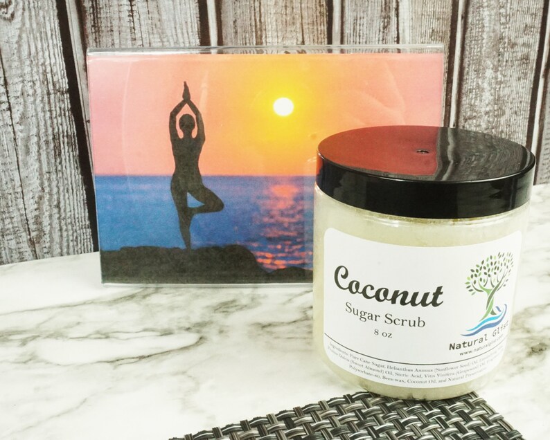 May include: A clear glass jar with a black lid filled with a white sugar scrub. The label reads "Coconut Sugar Scrub 8 oz Natural Gifts".