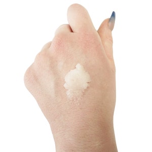 May include: A close-up of a hand with a white, grainy substance on the palm. The substance appears to be a scrub or exfoliant.