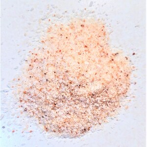 May include: A close-up of a pile of pink Himalayan salt crystals on a white surface.