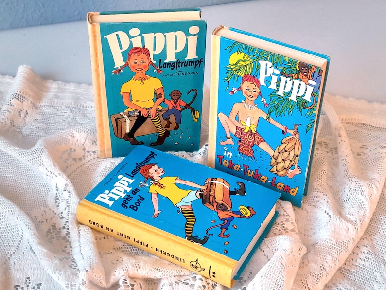 May include: Three vintage children's books with colorful illustrations. The books feature the title "Pippi" in large white letters on a blue background. The illustrations depict a young girl with red braids and various scenes.