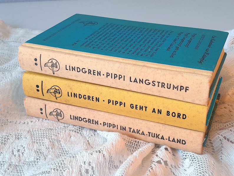 May include: Three vintage books stacked, featuring titles in German. The top book has a teal cover, while the others have cream and yellow spines. The titles include "Pippi Langstrumpf" and "Pippi Geht An Bord."