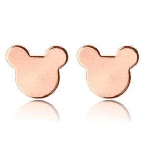 Pode incluir: Um par de brincos de bot&atilde;o em ouro rosa em forma de cabe&ccedil;a de rato. Os brincos t&ecirc;m um acabamento liso e polido e um design minimalista. S&atilde;o apresentados sobre um fundo branco.