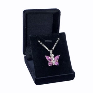 May include: A pink butterfly pendant necklace in a black velvet jewelry box.