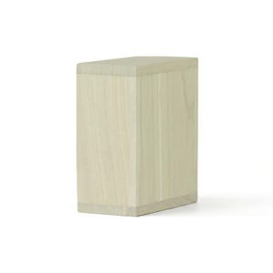 May include: A light-colored, rectangular wooden box with a slightly angled top. The box is made of light-colored wood with visible grain patterns. The design is simple and modern, with clean lines and a minimalist aesthetic.