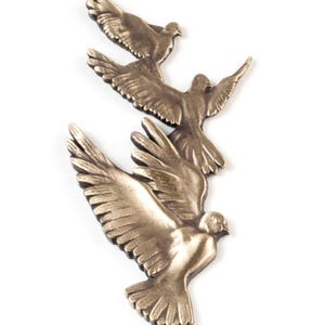May include: A decorative wall hanging featuring three bronze-colored birds in flight, arranged in a vertical formation. Each bird is depicted with wings spread wide, showing detailed feather textures and a metallic finish with dark highlights.