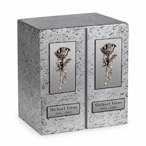 May include: A rectangular gray granite cremation urn with a speckled texture. It features two vertical brushed metal panels, each displaying a raised silver rose emblem. Below each rose is a metal plaque engraved with Michael Viens 1935-2005.