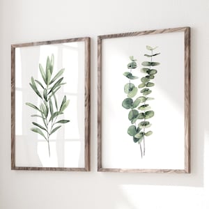 Set of 2 minimalist watercolor eucalyptus paintings  hang in wooden frames in modern hallway abave a wooden bench. The fine art posters are available in all sizes.