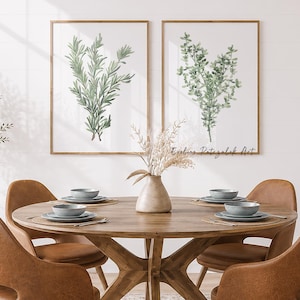 Peut inclure: Une table à manger ronde en bois avec quatre chaises rembourrées marron, un vase beige avec des tiges séchées et des couverts. Deux cadres botaniques d'herbes vertes sont accrochés au mur, avec la signature Eveline Patizebek Art.
