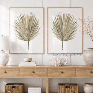 Peut inclure: Deux cadres muraux représentant des feuilles de palmier beiges sur fond blanc, disposés au-dessus d'une longue console en bois à quatre tiroirs et étagère inférieure, avec une lampe blanche, des livres, un corail et un vase en céramique.