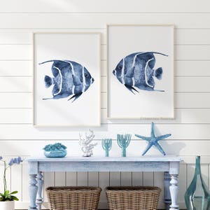 Peut inclure: Deux cadres muraux présentant des illustrations à l'aquarelle de poissons-anges bleus avec des rayures verticales blanches sur fond blanc. Les poissons sont représentés de profil, mettant en valeur des textures aquarelles détaillées.