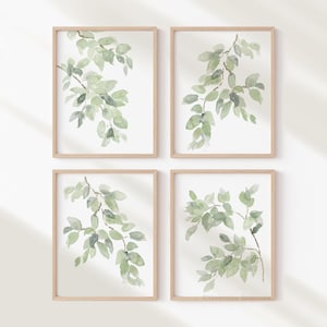May include: Set of four watercolor prints featuring green leaves on a white background. Each print is framed in a light wood frame.
