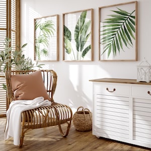 Set of 3 green tropical leaves on white background in frames, hung above a dresser. Beautiful minimalist wall decor located in the living room.