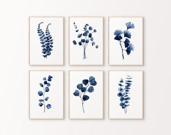 May include: Set of six indigo blue watercolor prints featuring various botanical illustrations of leaves and branches. The prints are framed in simple white frames.
