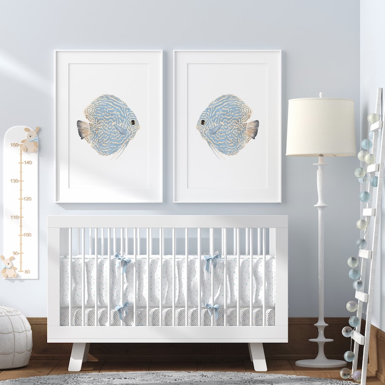 Watercolro set of 2 fish posters prints hangs above a crib in a baby boy nursery.