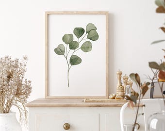 May include: A framed print of a watercolor painting of a eucalyptus branch with green leaves. The print is on a white background and is framed in a light wood frame.