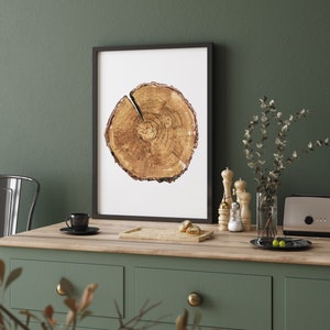 May include: A framed print of a tree trunk cross section with a white background. The print is hanging on a green wall above a wooden countertop with a black coffee cup and a small wooden tray with two pastries.