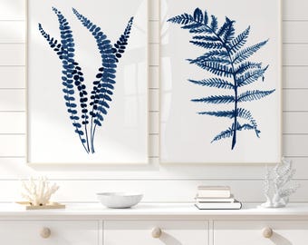 May include: Two framed botanical prints featuring indigo blue fern illustrations on a white background. The prints are displayed in light wood frames, adding a touch of natural elegance to the wall decor. The artwork is a perfect addition to any home.