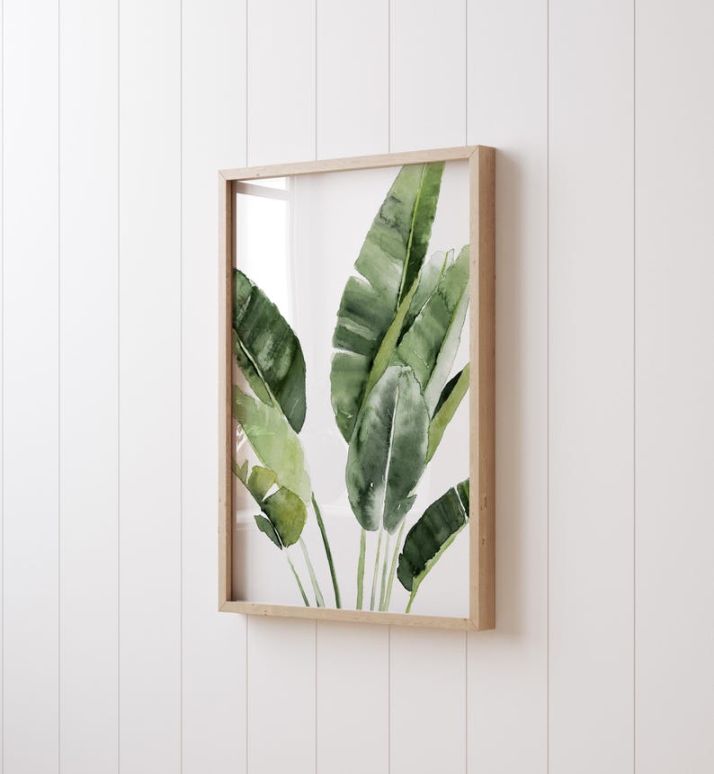 May include: A framed watercolor painting of green banana leaves on a white background.