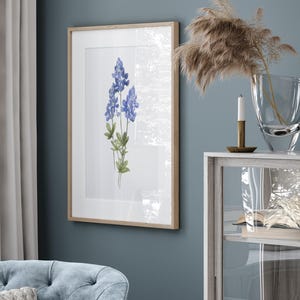 K&ouml;nnte beinhalten: Ein gerahmtes Aquarellbild von Blausternblumen, einer Wildblumenart, die in Texas heimisch ist, vor einem wei&szlig;en Hintergrund. Der Rahmen ist aus hellem Holz.