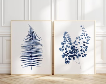 May include: Two framed watercolor prints of blue fern leaves. The print on the left features a single fern leaf, while the print on the right features a cluster of fern leaves.