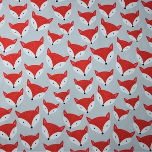 May include: A grey fabric with a repeating pattern of red fox faces. The fabric is shown with a measuring tape.