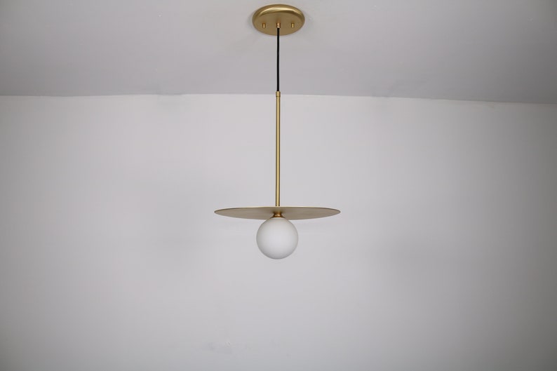 May include: A gold pendant light with a white globe shade and a flat, circular canopy.