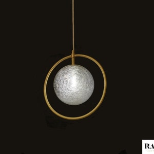 May include: A gold pendant light with a frosted glass globe suspended within a circular frame.