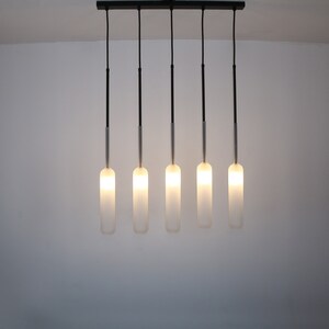 May include: A modern light fixture with five frosted glass bulbs hanging from a black metal bar.