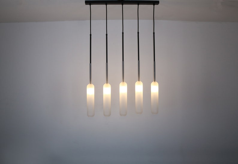 May include: A modern light fixture with five frosted glass bulbs hanging from a black metal bar.