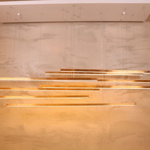 May include: A modern gold-toned light fixture with multiple horizontal bars hanging from the ceiling.