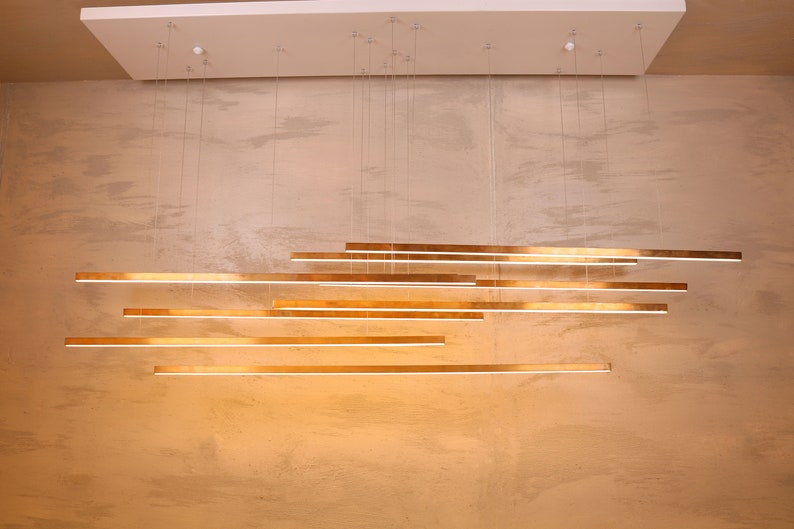 May include: A modern gold-toned light fixture with multiple horizontal bars hanging from the ceiling.