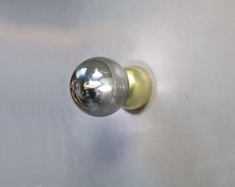 May include: A silver and gold door knob with a round, reflective surface.