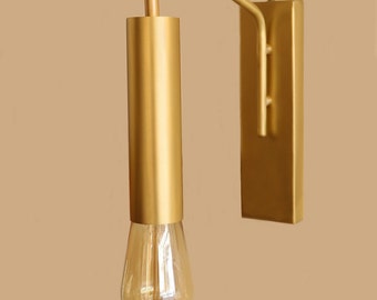 May include: Gold wall sconce with a single light bulb. The sconce has a long, curved arm and a rectangular base.