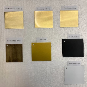 Puede incluir: Una comparaci&oacute;n de diferentes acabados de lat&oacute;n, incluyendo lat&oacute;n sin laca oxidado, lat&oacute;n lacado brillante, lat&oacute;n lacado mate, lat&oacute;n ennegrecido, color dorado, color negro mate y color blanco mate.