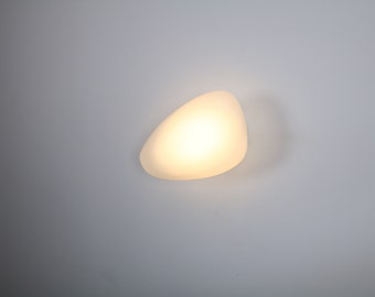 May include: A white, pebble-shaped light fixture mounted on a white ceiling.