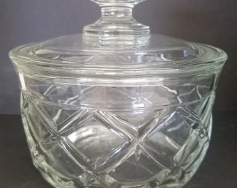 Könnte beinhalten: Eine klare Glasdose mit Deckel, die ein Diamantenmuster aufweist. Die Dose hat einen runden Körper und einen leicht ausgestellten oberen Teil. Der Deckel hat einen Knopf oben.