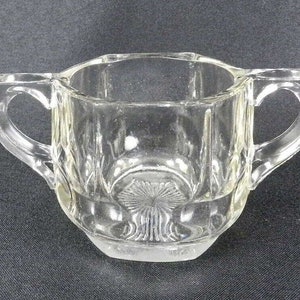 以下が含まれることがあります： 2つの取っ手のある透明なガラス製の砂糖入れ。ボウルはファセットデザインで、丸い底になっています。