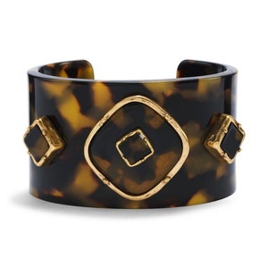 May include: A wide brown and black tortoiseshell resin bangle bracelet with gold accents and black square stones.