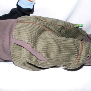 May include: A pair of green corduroy trousers with brown stitching. The trousers have a brown waistband and are turned up at the ankles.