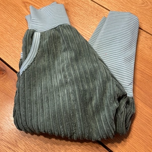 Könnte beinhalten: Eine grüne Cordhose mit einem hellblauen und weißen gestreiften Bund und Bündchen.