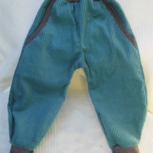 Puede incluir: Pantal&oacute;n de pana turquesa con cintura y pu&ntilde;os de canal&eacute; grises. El pantal&oacute;n tiene bolsillos grandes a los lados.