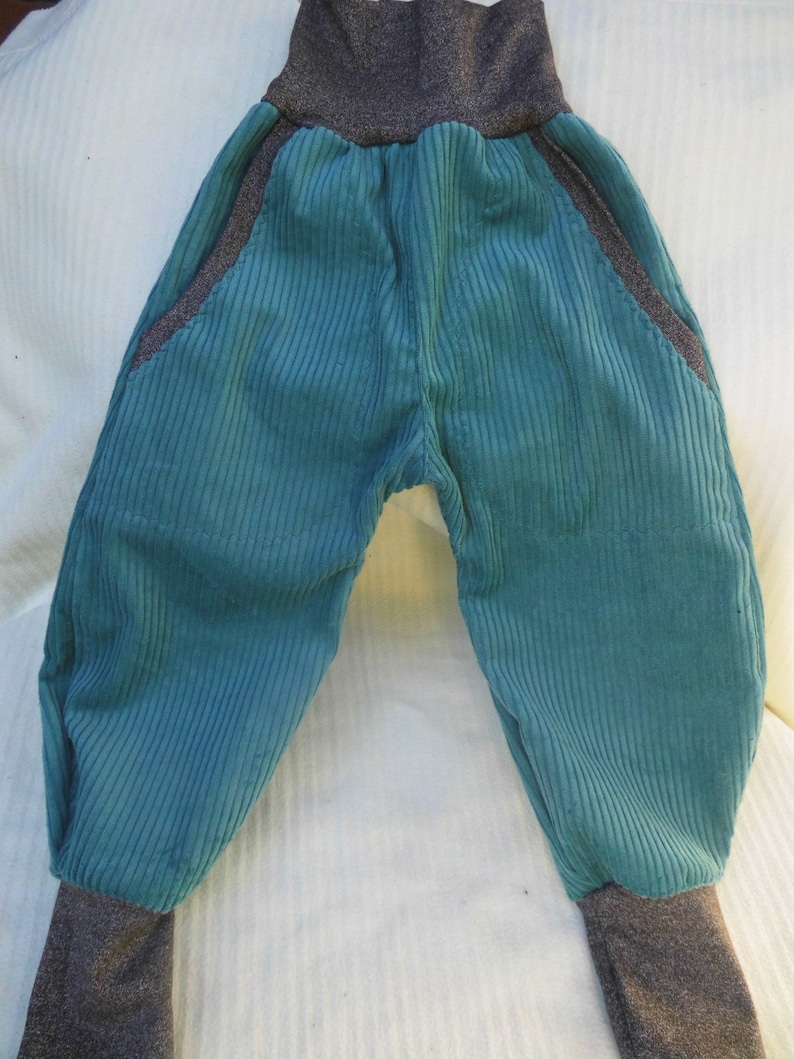 Puede incluir: Pantal&oacute;n de pana turquesa con cintura y pu&ntilde;os de canal&eacute; grises. El pantal&oacute;n tiene bolsillos grandes a los lados.