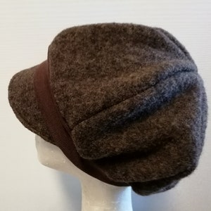 Könnte beinhalten: Eine braune Mütze aus Fleece im Newsboy-Stil mit braunem Bandbesatz.