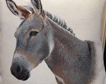 May include: A close-up of a gray donkey's head and neck. The donkey is looking to the left of the image. The donkey's fur is a light gray with brown highlights. The donkey's ears are long and pointed. The donkey's eyes are dark and alert. The donkey's nose is black and wet. The donkey's mouth is closed. The donkey's mane is short and dark. The donkey's neck is thick and muscular. The donkey's body is not visible in the image. The donkey is on a white background.